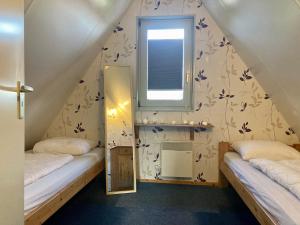 Habitación pequeña con 2 camas y ventana en De Druif 6 pers holiday home close to the National Park Lauwersmeer, en Anjum