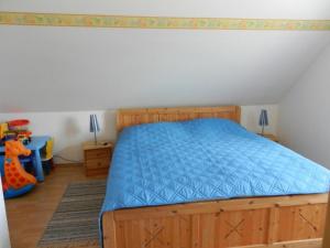 Schlafzimmer mit einem Holzbett mit blauer Tagesdecke in der Unterkunft Ferienhaus Seehund in Krummhörn