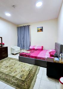 Un dormitorio con una cama con sábanas rosas y una mesa. en Anju's sweet Stay en Sharjah