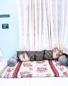 a couch with pillows sitting in front of a curtain at Rooftop Floor with a big Room in New Delhi