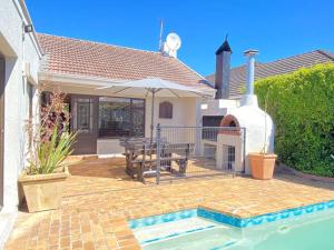 Casa con patio con mesa y sombrilla en A Home in Timour Hall, en Ciudad del Cabo