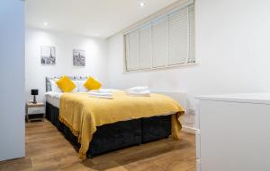 a bedroom with a bed with yellow pillows and a window at Smart Central Woking 1 Bedroom Apartment in Woking