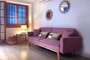 un sofá púrpura en una sala de estar con espejo en Apartamentos Vela Blanca, en San José