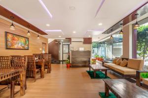a restaurant with wooden tables and chairs and a couch at Treebo Trend Purple Square in Hyderabad