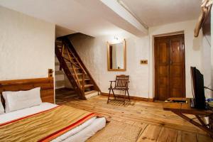 1 dormitorio con 1 cama y escalera con TV en Chevron Eco Lodge Kausani, en Kausani