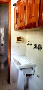 y baño con lavabo blanco y armarios de madera. en Local privilegiado em Aguas ! en Águas de Lindóia