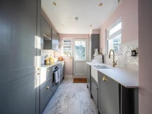 a kitchen with gray cabinets and a white tile floor at Pass the Keys Boutique apartment 15 mins bus to Central London in London