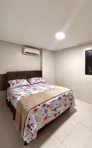 um quarto com uma cama com um edredão e almofadas em Apto confort bem localizado Macambira em Campina Grande