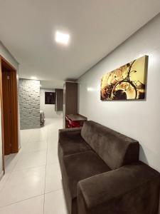 uma sala de estar com um sofá e uma pintura na parede em Apto confort bem localizado Macambira em Campina Grande