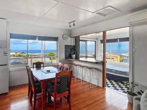 a dining room with a table and chairs and a kitchen at Wave Side Cottage Scamander Sleeps 5 in Scamander