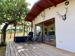 a house with a wooden deck with chairs and a table at Landhaus Waidblick in Wischeid