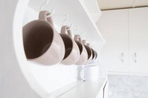 a row of white cups hanging on a wall at Wave Side Cottage Scamander Sleeps 5 in Scamander +27 photos