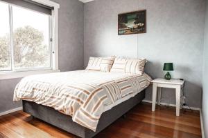 een slaapkamer met een bed, een raam en een tafel bij Wave Side Cottage Scamander Sleeps 5 in Scamander