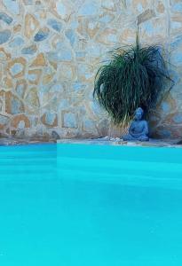 a statue sitting next to a stone wall with a plant at MoonLava: Apto, Piscina, WiFi in Yaiza