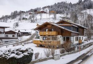 une maison avec un balcon dans la neige dans l'établissement Hotel Austria - inklusive Joker Card im Sommer, à Saalbach-Hinterglemm