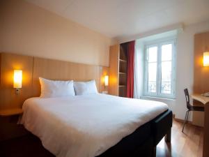 Schlafzimmer mit einem großen weißen Bett und einem Fenster in der Unterkunft ibis Limoges Centre in Limoges