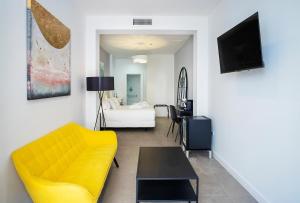a living room with a yellow couch and a table at The Old Town Boutique Hotel - Adults Only in Estepona