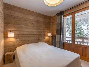 ラ・クリュサにあるAppartement La Clusaz, 4 pièces, 8 personnes - FR-1-304-205の木製の壁のベッドルーム1室、窓付きのベッド1台が備わります。