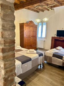 a bedroom with two beds and a stone wall at Green Rooms Ferrara in Ferrara