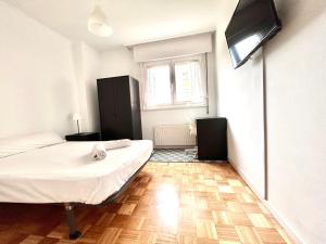 1 dormitorio con 1 cama y TV en la pared en VibesCoruña - Madariaga 41, en A Coruña