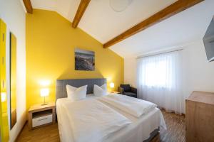 ein Schlafzimmer mit einem weißen Bett und einer gelben Wand in der Unterkunft Ferienwohnung "Bernstein" im Ostsee-Domizil Sandburg in Kühlungsborn