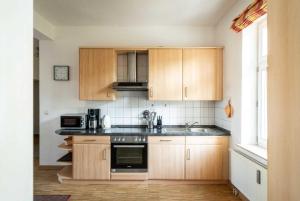 eine Küche mit Holzschränken und einem Herd mit Backofen in der Unterkunft Ferienwohnung "Abendsonne" im Ostsee-Domizil Sandburg in Kühlungsborn