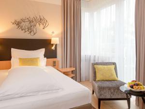 une chambre d'hôtel avec un lit et une chaise dans l'établissement Mercure Hotel Koeln Belfortstrasse, à Cologne