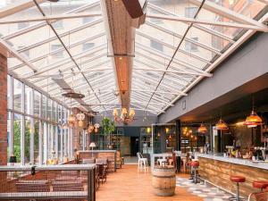 a restaurant with glass ceilings and tables and chairs at Novotel Cardiff Centre in Cardiff