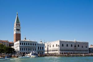 ein Gebäude auf dem Wasser mit einem Uhrturm in der Unterkunft at 1 minute from San Marco square in Venedig