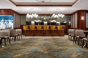 a conference room with a bar with chairs and tables at La Quinta by Wyndham Madison American Center in Madison