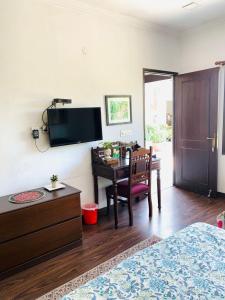a bedroom with a table and a desk with a television at Vandana's Bed and breakfast in New Delhi