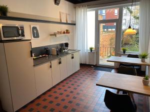 kuchnia z białymi szafkami, stołem i telewizorem w obiekcie Good Mood - chambres et suite w mieście Namur