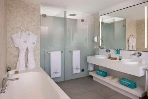 een badkamer met een bad, een wastafel en een spiegel bij Royal Hideaway Corales Suites in Adeje