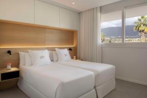 a bedroom with a large white bed with a window at Royal Hideaway Corales Suites in Adeje