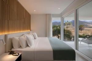 a bedroom with a large bed and a large window at Royal Hideaway Corales Suites in Adeje