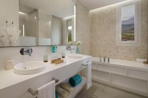 a bathroom with two sinks and a tub and a mirror at Royal Hideaway Corales Suites in Adeje