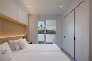a bedroom with a white bed and a large window at Royal Hideaway Corales Suites in Adeje