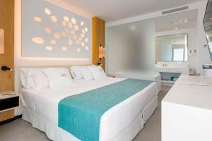 a bedroom with a large white bed and a bathroom at Royal Hideaway Corales Suites in Adeje