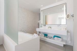 a bathroom with a tub and a sink and a mirror at Royal Hideaway Corales Suites in Adeje