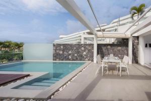 a villa with a swimming pool and a dining area at Royal Hideaway Corales Suites in Adeje
