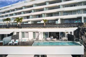 a large white building with a swimming pool at Royal Hideaway Corales Suites in Adeje