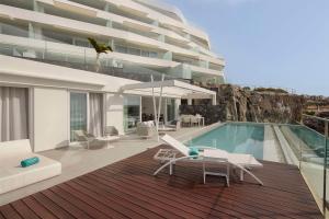 a house with a swimming pool next to a building at Royal Hideaway Corales Suites in Adeje