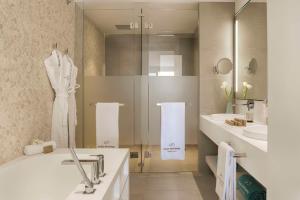 a bathroom with a shower and a tub and a sink at Royal Hideaway Corales Suites in Adeje