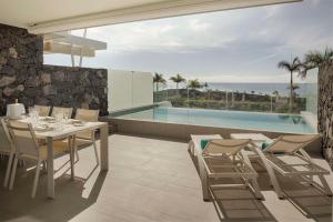 a dining room with a table and chairs and a pool at Royal Hideaway Corales Suites in Adeje