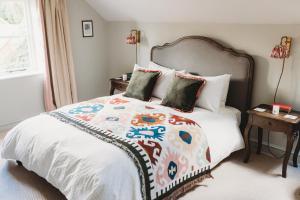 1 dormitorio con 1 cama con un edredón colorido en Luxury Cottage with Swimming Pool en Bredon