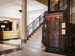 a lobby with a staircase with a wrought iron door at Raffles Grand Hotel d'Angkor in Siem Reap
