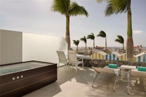 a patio with a hot tub and chairs and palm trees at Royal Hideaway Corales Beach - Adults Only in Adeje +37 photos