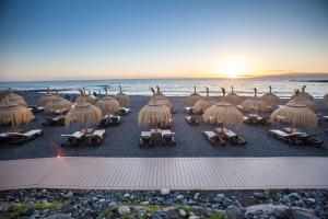 a group of chairs and straw umbrellas on a beach at Royal Hideaway Corales Beach - Adults Only in Adeje