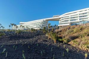 a building on a hill with plants in front of it at Royal Hideaway Corales Beach - Adults Only in Adeje