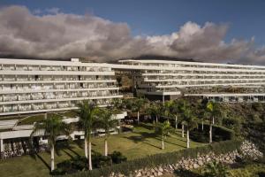 a large white building with palm trees in front of it at Royal Hideaway Corales Beach - Adults Only in Adeje